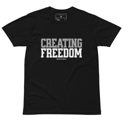 Black tee with bold gray and white text “Creating Freedom” and small “Brick by Brick” centered below.