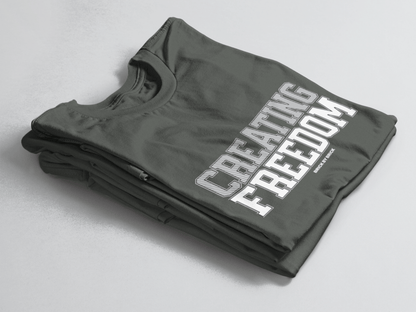 Charcoal Green folded tee with bold gray and white text “Creating Freedom” and small “Brick by Brick” centered below