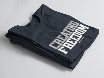 Navy folded tee with bold gray and white text “Creating Freedom” and small “Brick by Brick” centered below