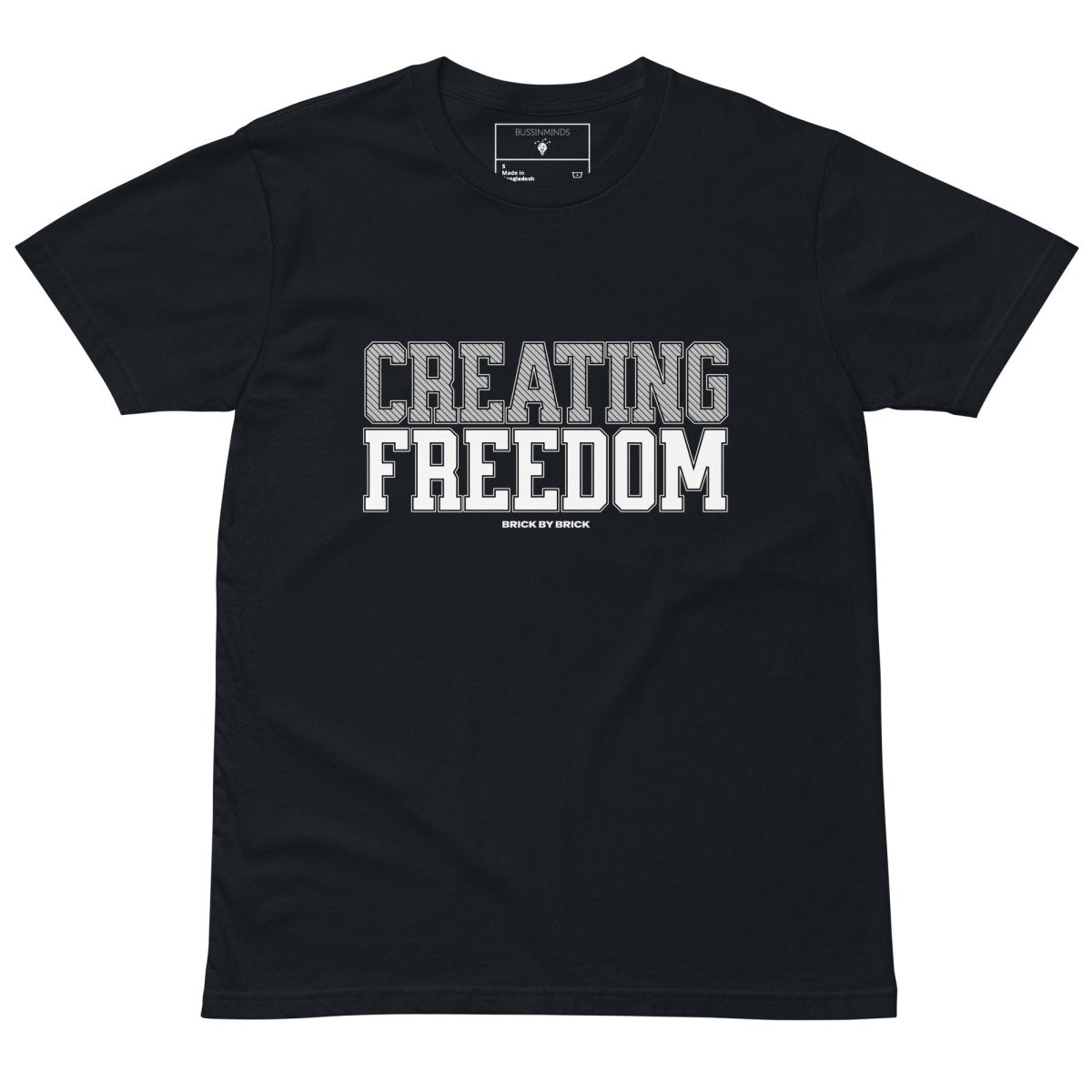 Navy tee with bold gray and white text “Creating Freedom” and small “Brick by Brick” centered below