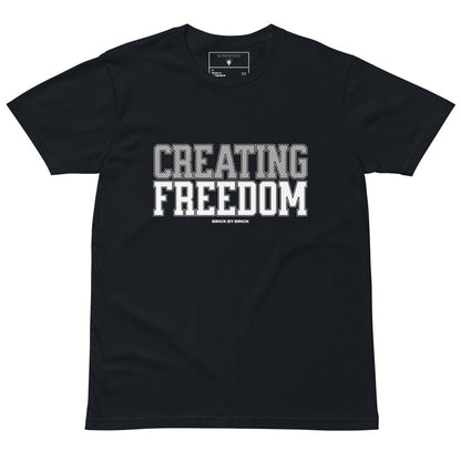 Navy tee with bold gray and white text “Creating Freedom” and small “Brick by Brick” centered below