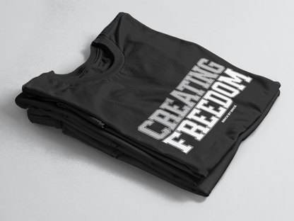 Black folded tee with bold gray and white text “Creating Freedom” and small “Brick by Brick” centered below.