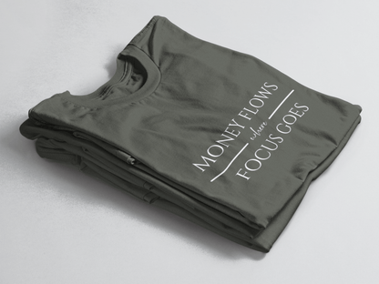 Greeb folded tee with white text “Money Flows Where Focus Goes” in elegant serif font, with horizontal lines next to “where"