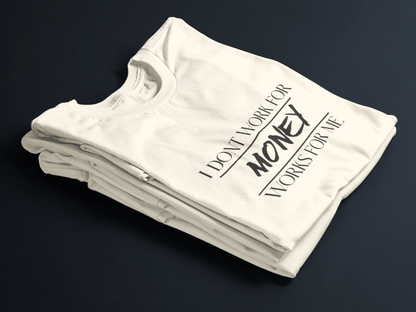 Beige folded tee with black text “I Don’t Work For Money, Money Works For Me” featuring “Money” in bold stylized font.