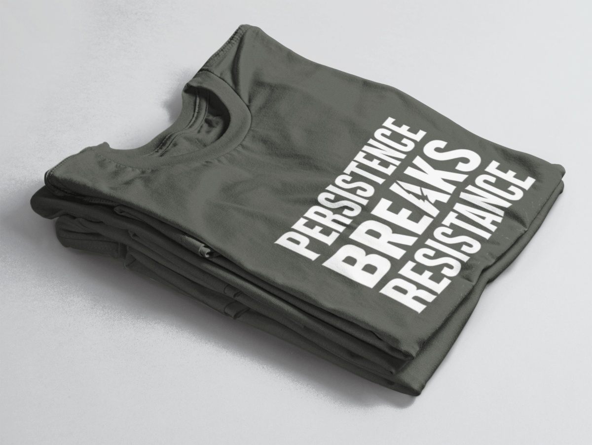 green folded t-shirt with bold white text “Persistence Breaks Resistance” and a lightning bolt in the letter “A” of BREAKS.