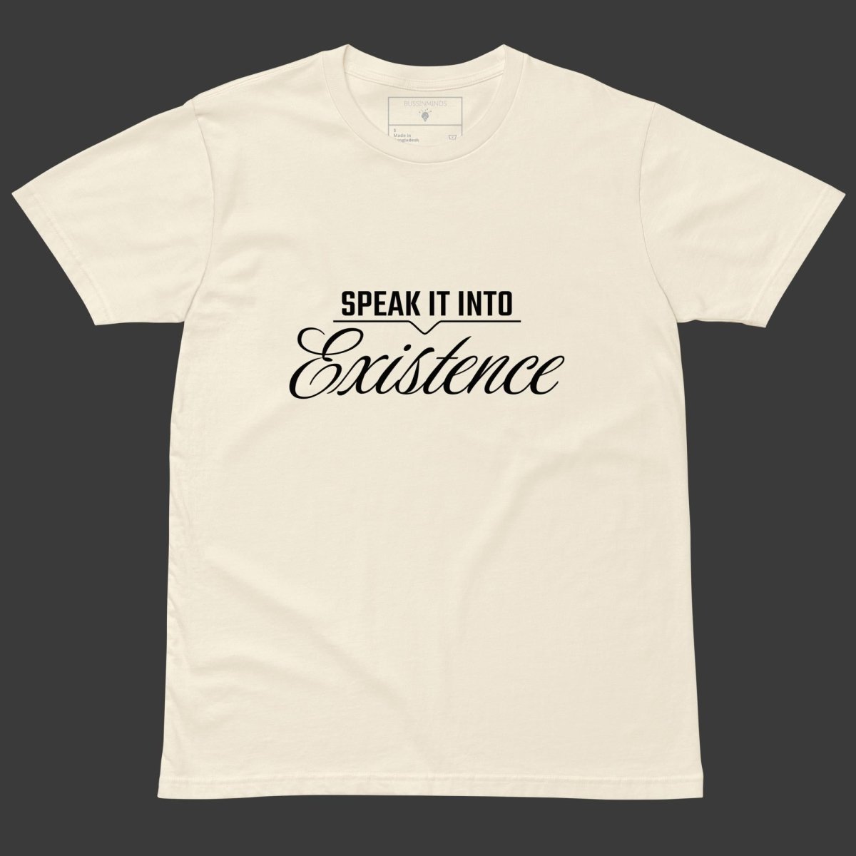 Beige tee with black text “Speak It Into” in bold caps above cursive “Existence” centered on the front.