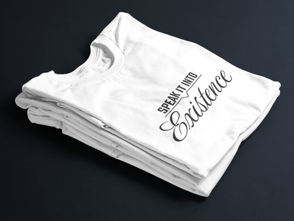White folded tee with black text “Speak It Into” in bold caps above cursive “Existence” centered on the front.