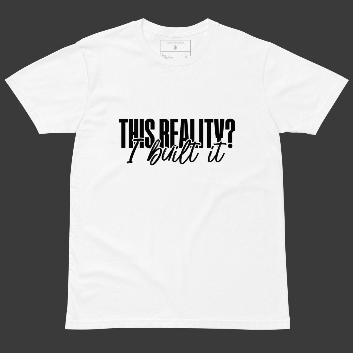 White tee with bold outlined text “This Reality?” above cursive “I built it” in white script.