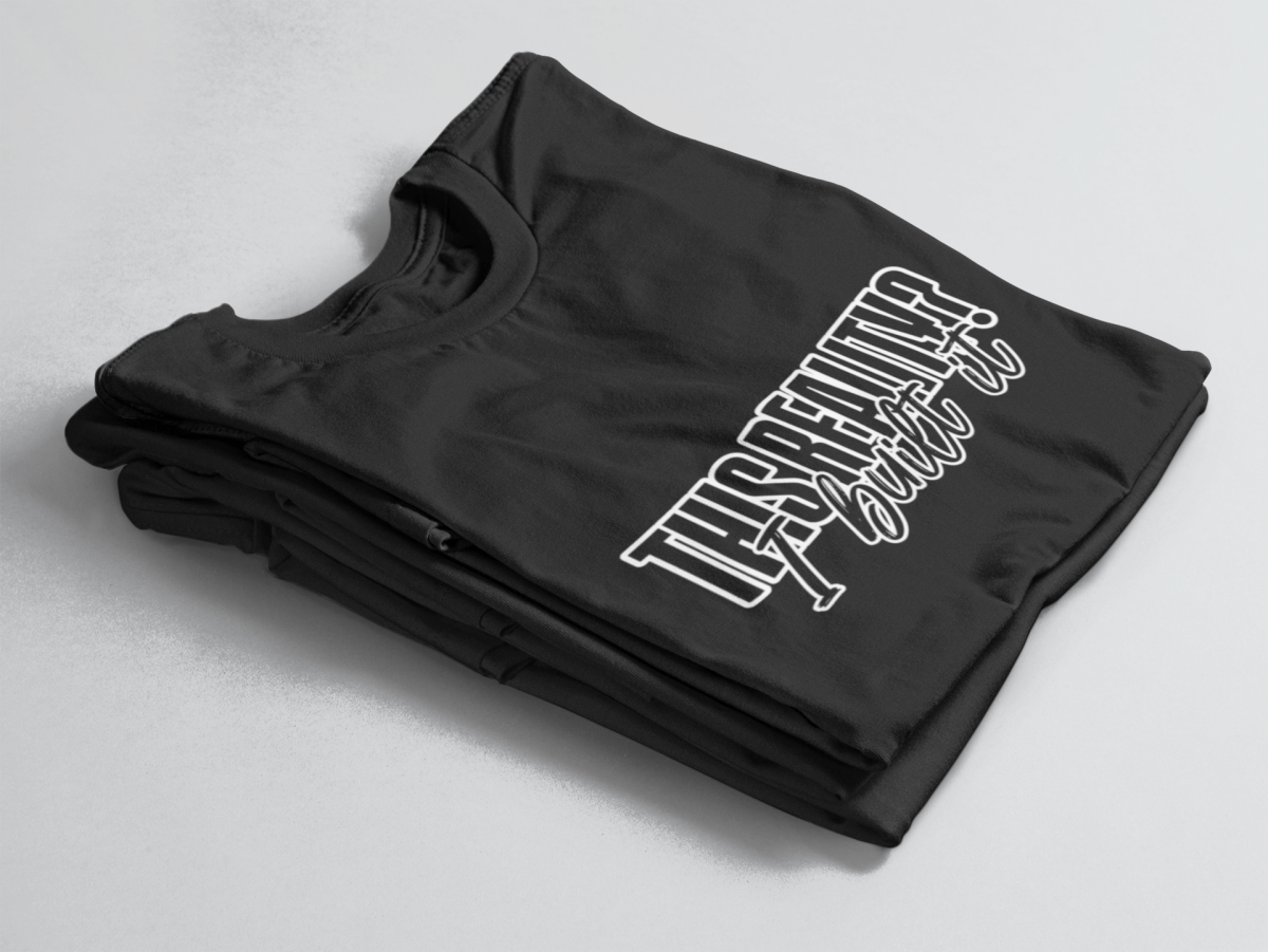 Black folded tee with bold outlined text “This Reality?” above cursive “I built it” in white script.