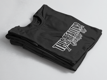 Black folded tee with bold outlined text “This Reality?” above cursive “I built it” in white script.